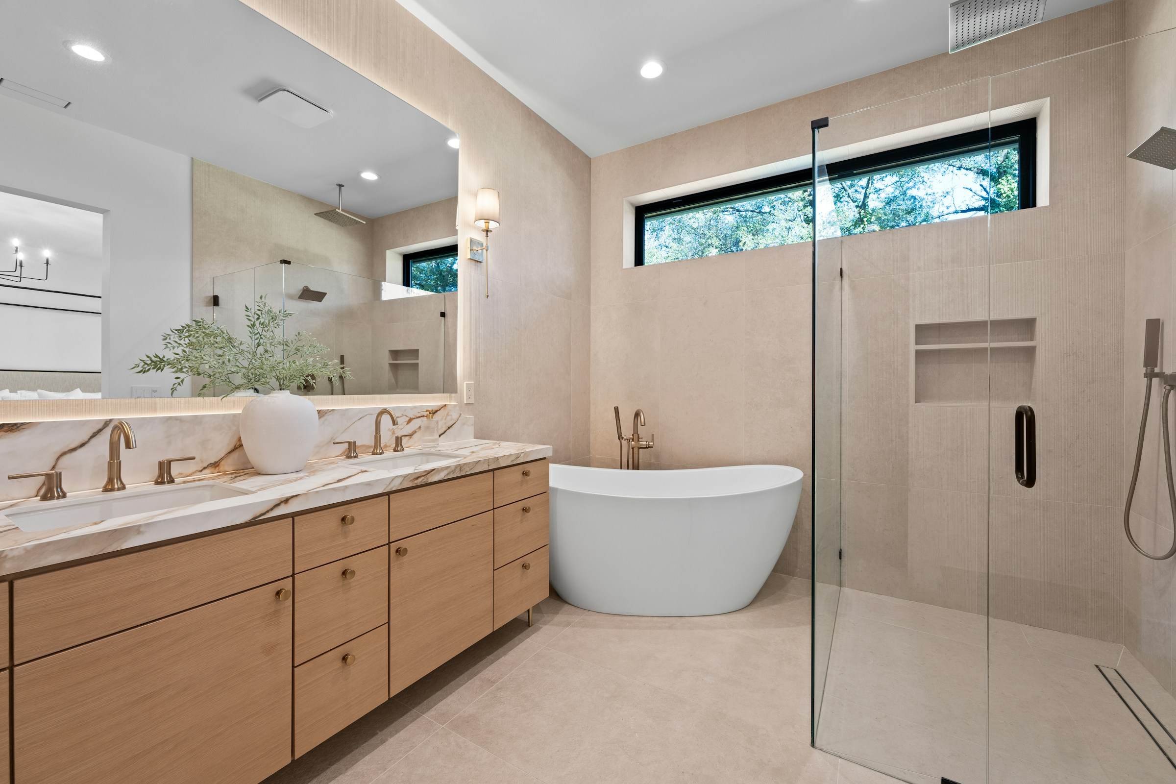 Bright bathroom with oak double vanity, freestanding tub and frameless glass shower
