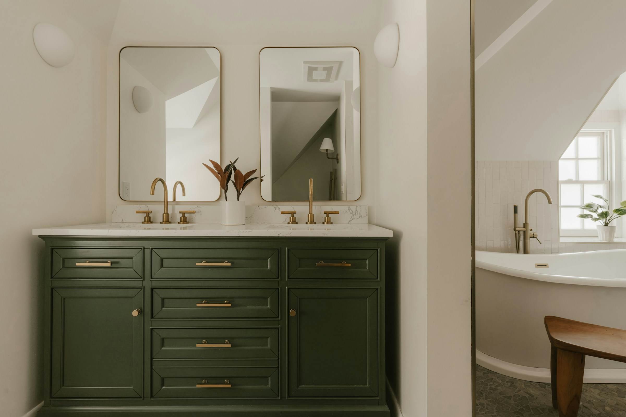 Green painted vanity with brass taps, twin mirrors and a freestanding bath