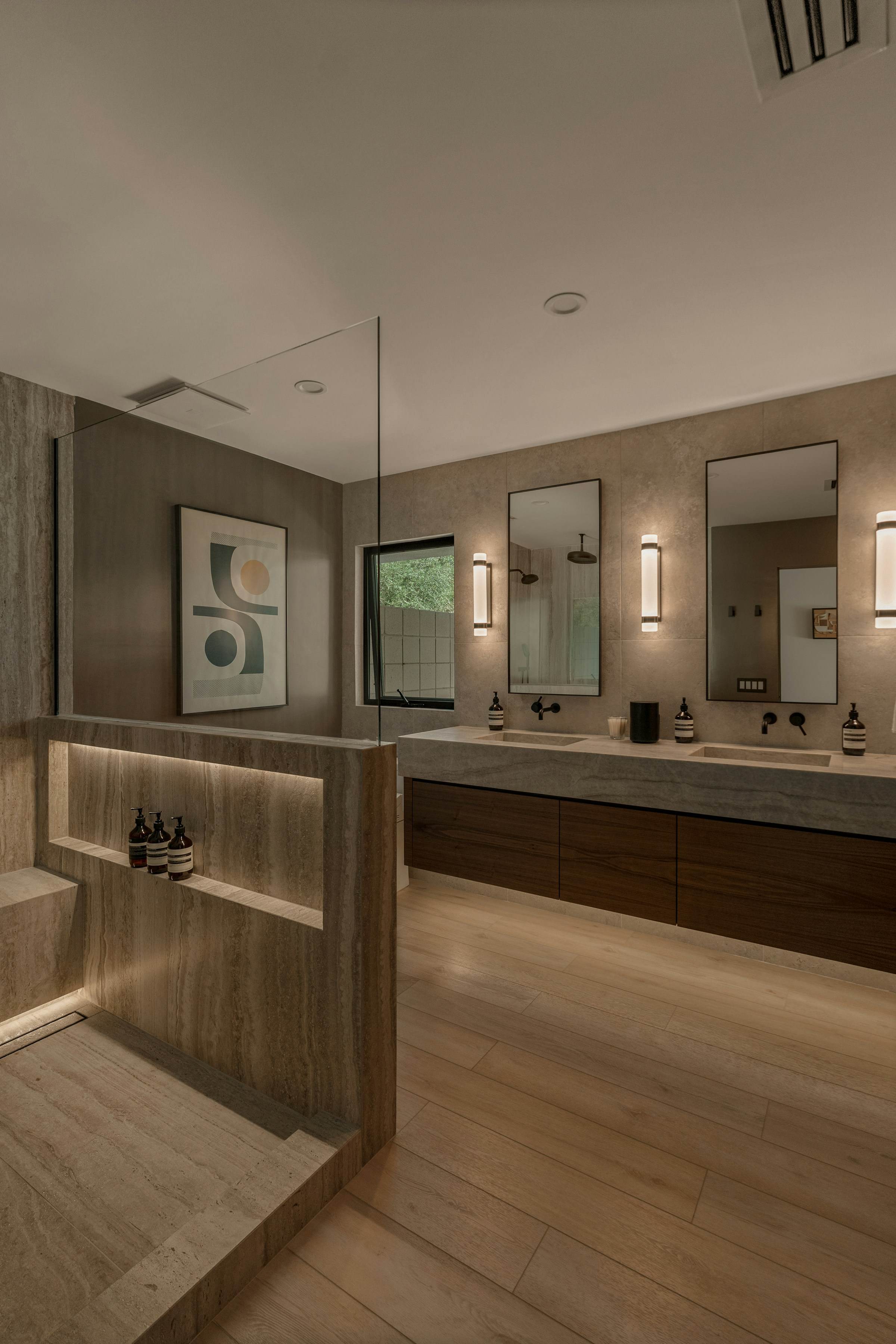 Travertine ensuite with a lit shower niche and floating walnut vanity