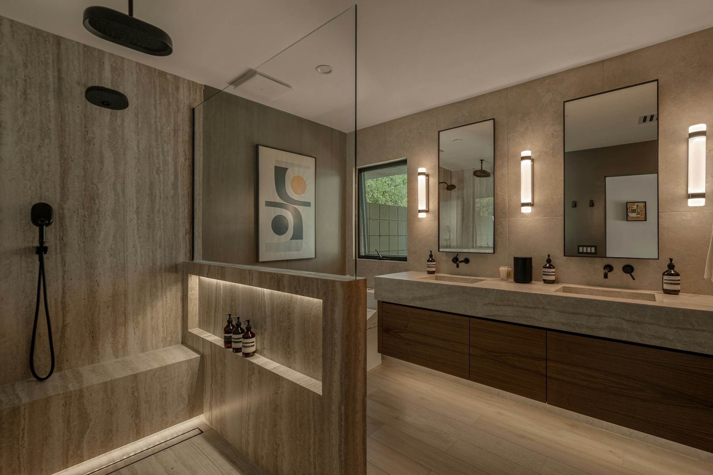 Primary ensuite finished in travertine, with a walk-in shower, lit niche and double floating vanity