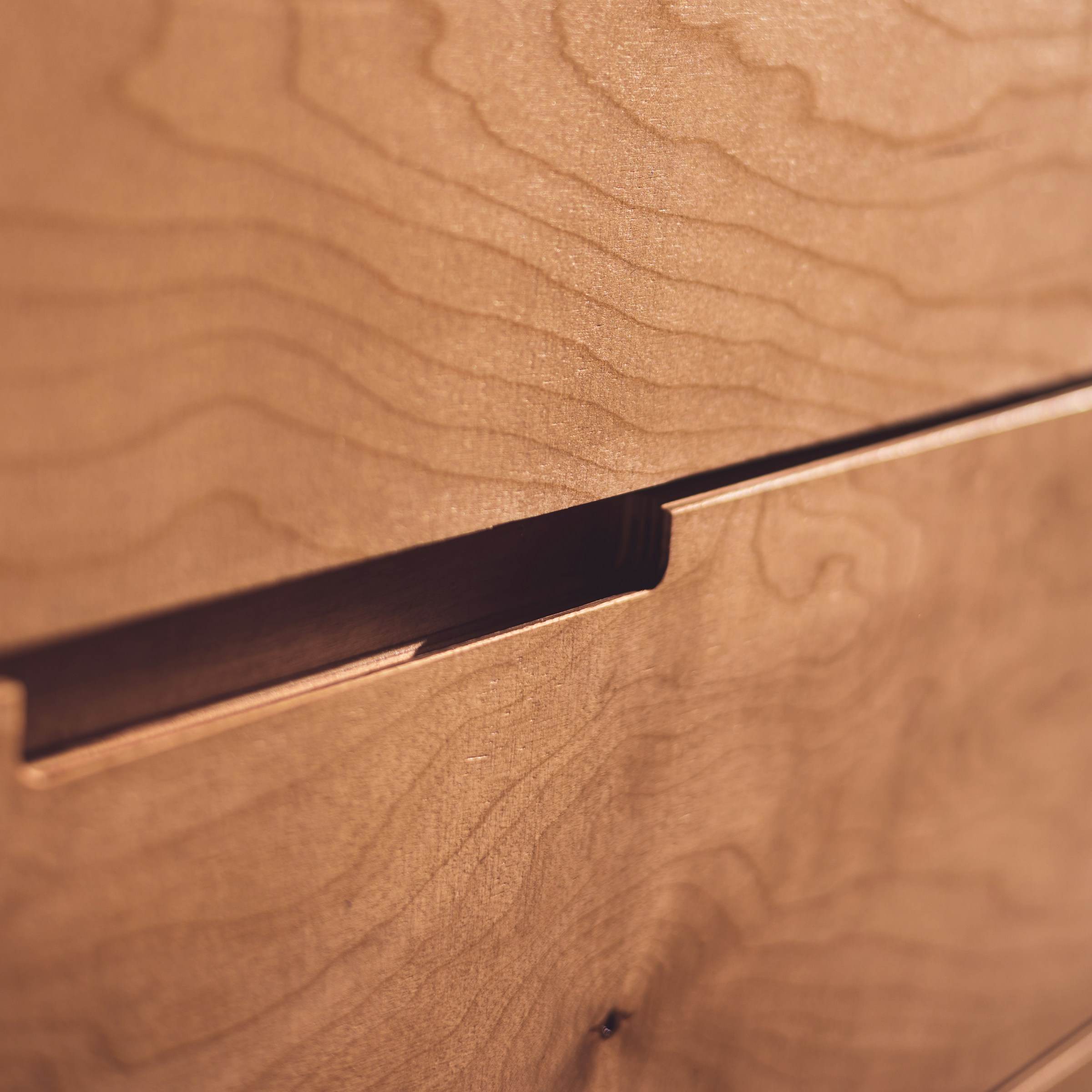 Close-up of a routed finger pull in figured timber cabinetry