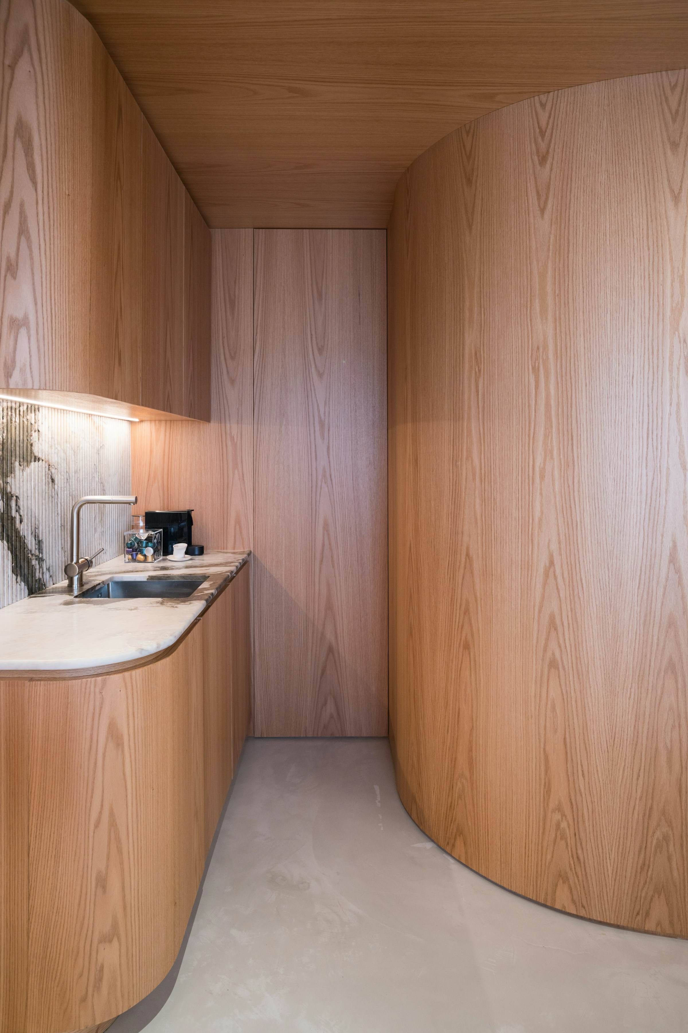 Curved oak-panelled room with an integrated counter and stone backsplash