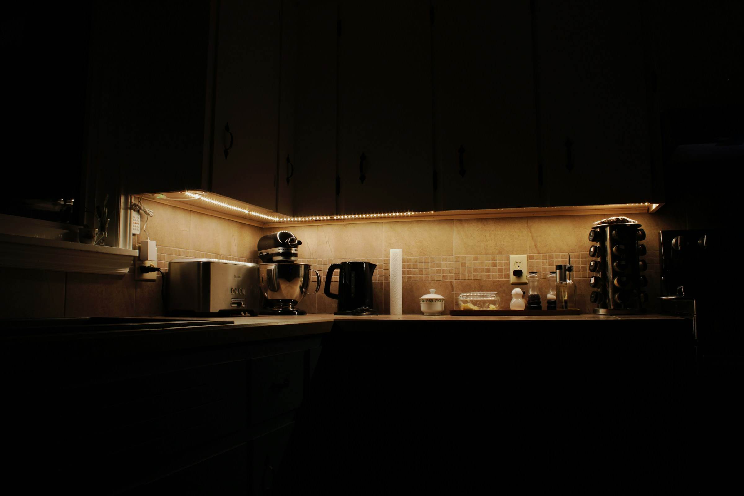 Warm LED under-cabinet lighting along a kitchen counter at night