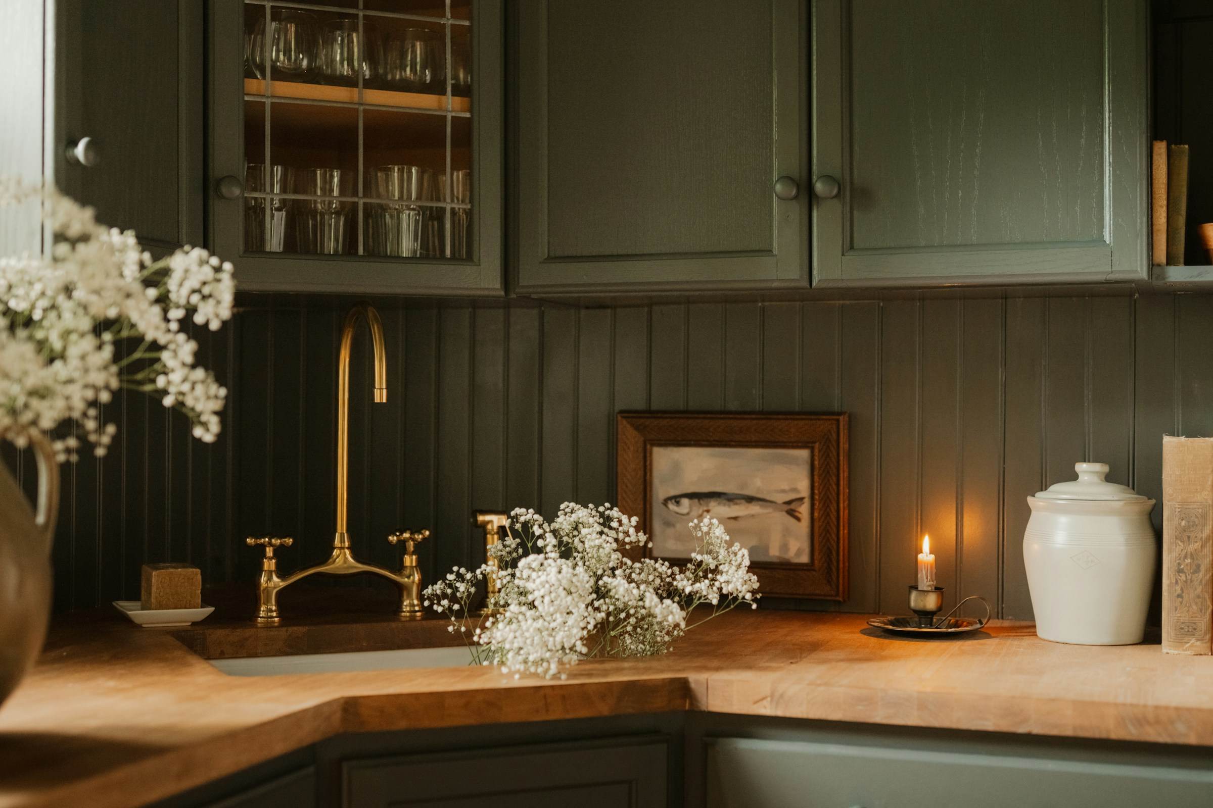 Deep green shaker cabinets, butcher-block counter and an unlacquered brass bridge tap