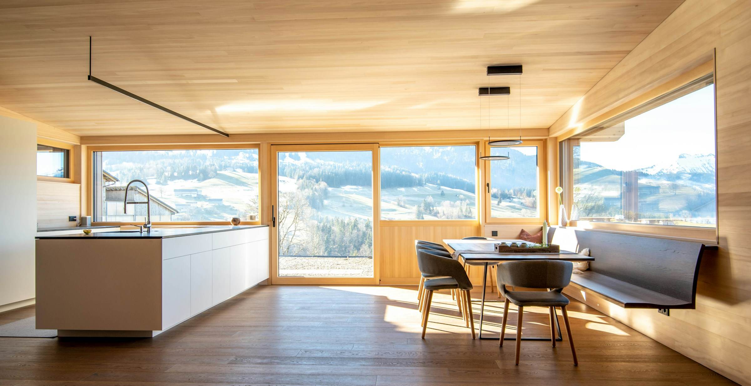 Timber kitchen and dining space with built-in bench seating along a long window